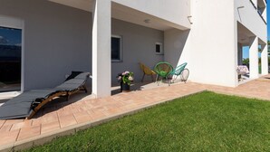 A modern building with a covered patio area, a lounge chair, and a small garden. - Apartment Sankovic (Rovinj)