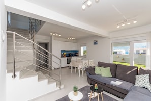 Uma sala de estar moderna com escada, área de jantar e cozinha.