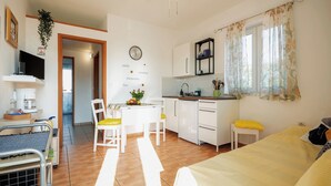 A compact living space with a kitchenette, a dining area, and a bed. - Apartments Kamenar (Dobrinj)