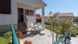 A covered outdoor patio with a table and chairs, a small step leading to the entrance, and a potted plant. - House Casa Jelena (Kastelir-Labinci)