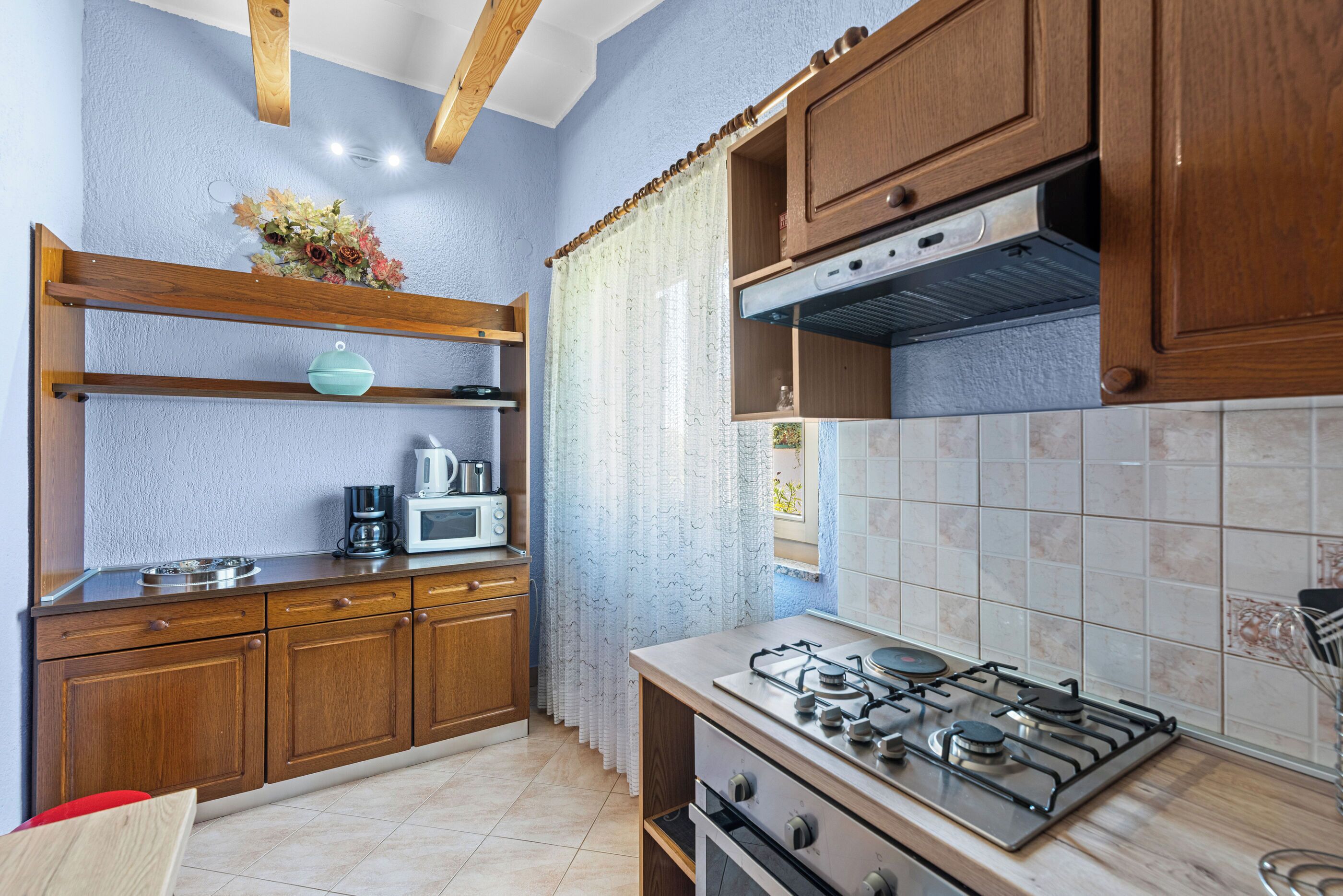 A kitchen with wooden cabinets, a gas stove, a microwave, and a coffee maker.