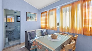 A compact room with a dining table, chairs, a sofa, a small sink, and a window with curtains. - House Casa Jelena (Kastelir-Labinci)