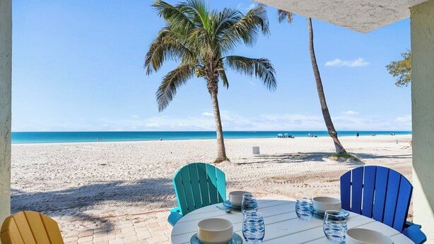 Ein Tisch mit Stühlen am Strand, mit Blick auf den Strand und das Meer.