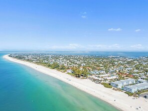 Eine Luftaufnahme einer Küstenstadt mit Strand, Wohnhäusern und einem großen Hotelkomplex.