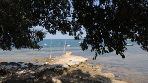 A beach with a stone structure, a sandy area, and boats in the water. - Apartment Monte (Umag)