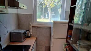 A compact kitchen with a microwave, refrigerator, and sink. A window provides natural light, and the floor is tiled. - Apartment Monte (Umag)