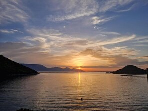 A sunset over a calm lake with mountains in the background. - Apartments Damir (Slivno)