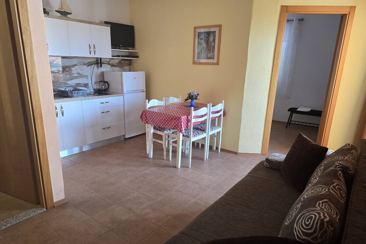 A compact living space with a kitchenette, a dining area with a table and chairs, and a sofa.