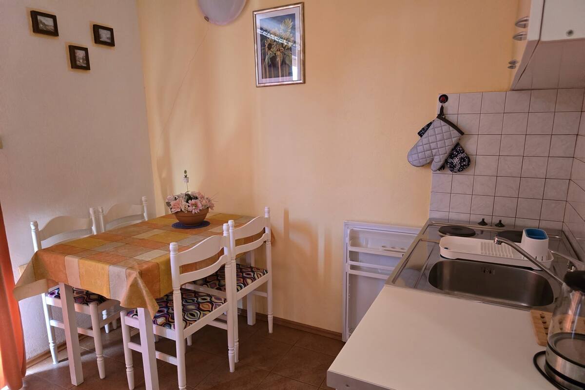 A kitchen with a dining table, chairs, a sink, and a stove.