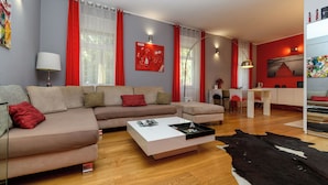 A modern living room with a sofa, coffee table, and a dining area with a table and chairs. - Apartment Mandria (Opatija)