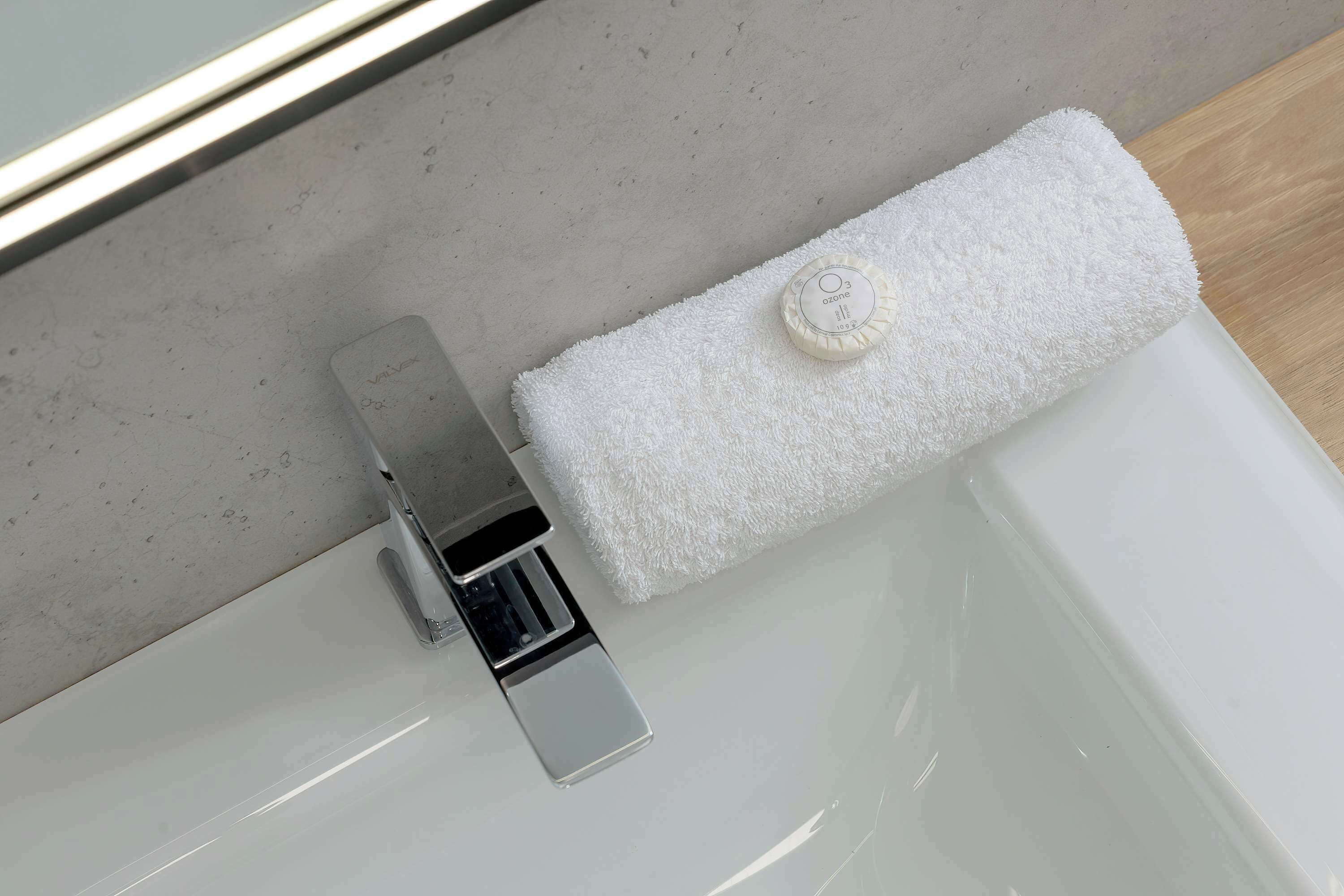 A white towel on a white bathtub with a chrome faucet.