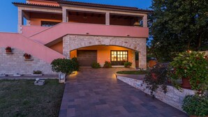 A two-story house with a stone facade, a covered porch, and a driveway leading to a dark entrance. - Apartment Damjan (Kastelir-Labinci)