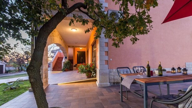 An outdoor patio area with a table set for dining, a potted tree, and a staircase leading to an entrance. - Apartment Damjan (Kastelir-Labinci)