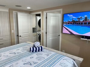 Ein Hotelzimmer mit einem Bett, einem Fernseher, der einen Pool zeigt, und einer Waschgelegenheit.