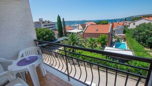 A balcony with a view of a swimming pool, a white chair, and a table. - Apartments Dalmatino (Biograd na Moru)