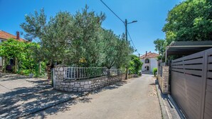 A quiet residential street with a stone wall, metal fence, and a clear blue sky. - Apartments Dalmatino (Biograd na Moru)