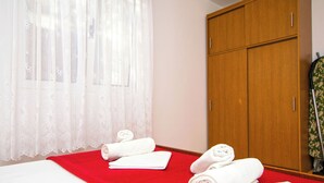 Una habitación de hotel con una cama, una colcha roja y toallas dobladas con esmero.