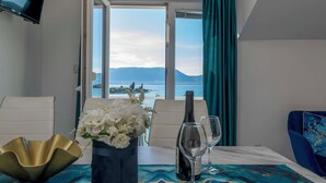 A room with a table set for two, a bottle of wine, and a vase of flowers. - Apartments Beach House Blace (Slivno)
