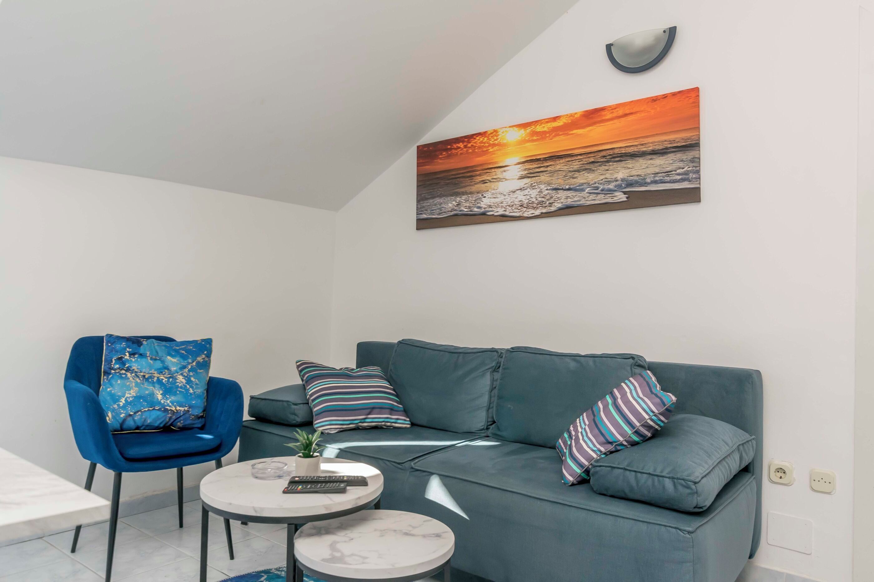 A modern living room with a grey sofa, a blue armchair, and a small round table.