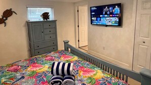Ein Schlafzimmer mit einem Bett, einem Schminktisch, einem Fernseher und einer Deckenleuchte.
