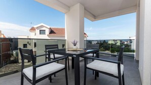Ein Balkon mit Glastisch und Stühlen, einem Blumentopf und Blick auf die Nachbarhäuser.