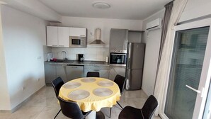 A compact kitchen with a dining table, chairs, and modern appliances. - Apartments Pajo Plus (Primosten)