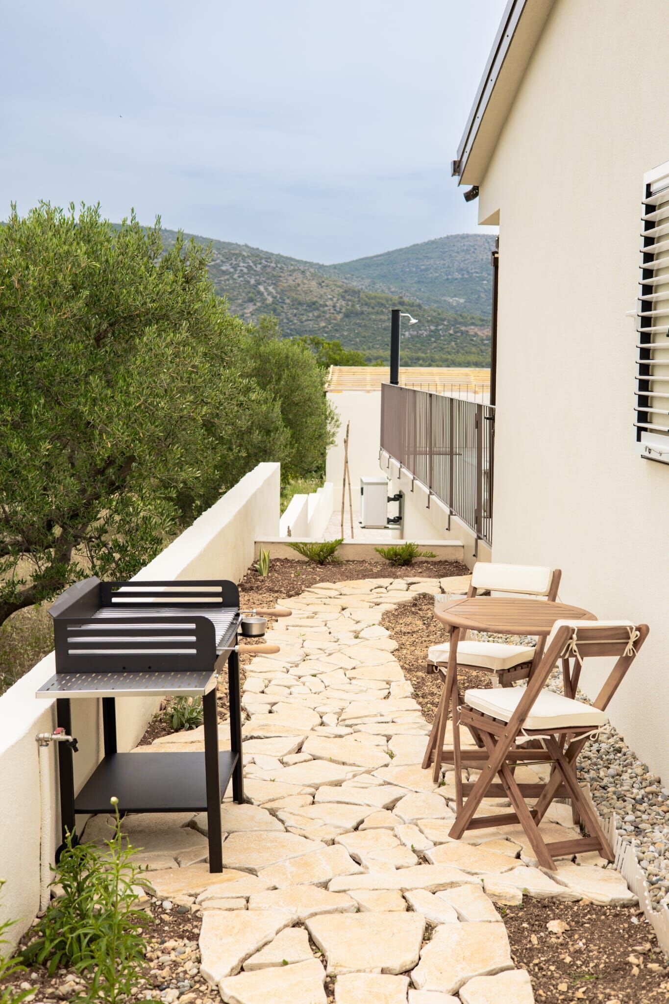 Un patio con una parrilla, mobiliario exterior y vistas a las colinas.