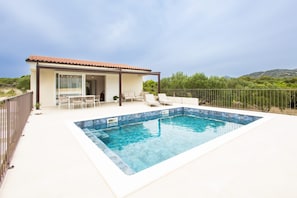 A modern villa with a swimming pool, outdoor seating, and a view of the surrounding landscape. - House Vrsinka (Marina)