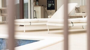 A modern outdoor lounge area with white lounge chairs and a pool. - House Vrsinka (Marina)