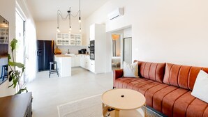 A modern living room with a brown sofa, a round coffee table, and a kitchen in the background. - House Vrsinka (Marina)