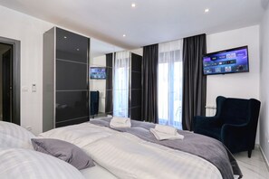 Quarto de hotel com uma cama, televisão fixada na parede e uma cadeira.