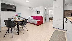 A modern living space with a dining area, a red sofa, and a kitchen. - Apartment Gradina (Vodnjan)