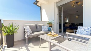 A balcony with a sofa, a table, and a potted plant. - Apartments Sunny (Vodice)
