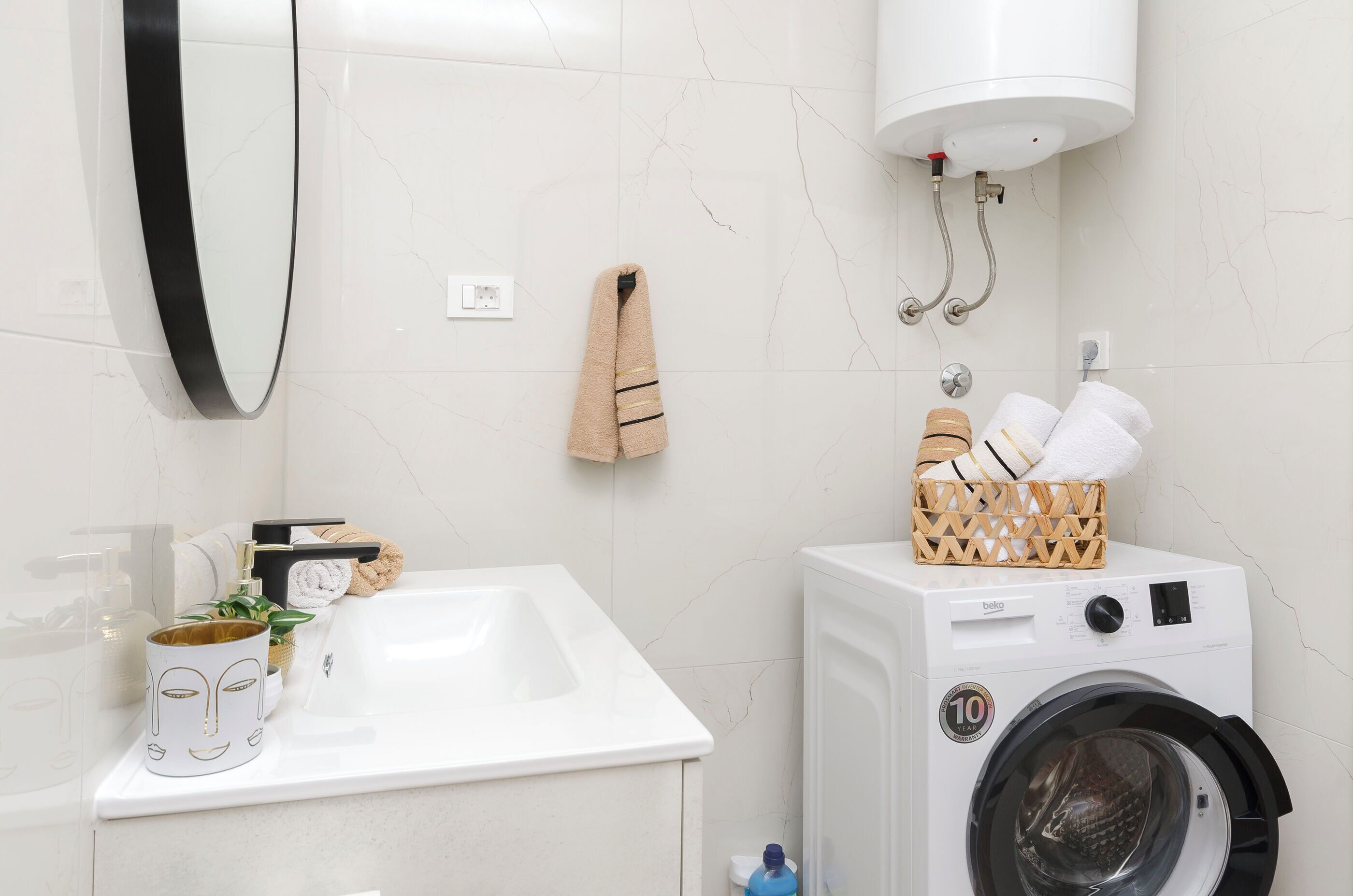 Ein Badezimmer mit Waschbecken, Spiegel, Handtuchhalter und Waschmaschine.