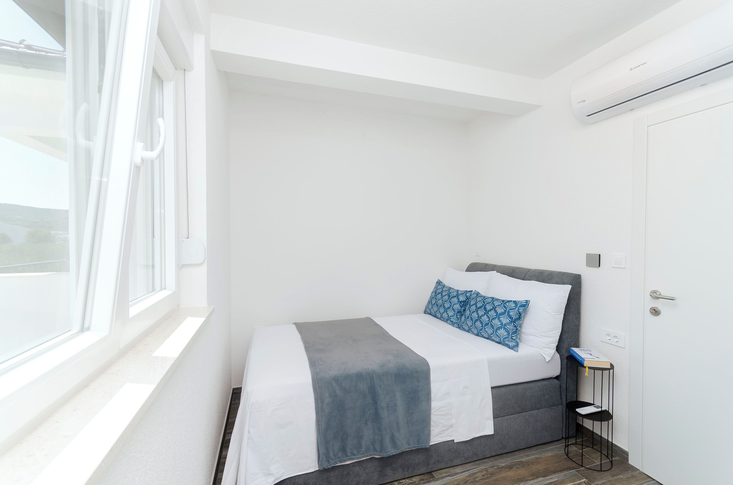 A small, bright room with a bed, a window, and a door.