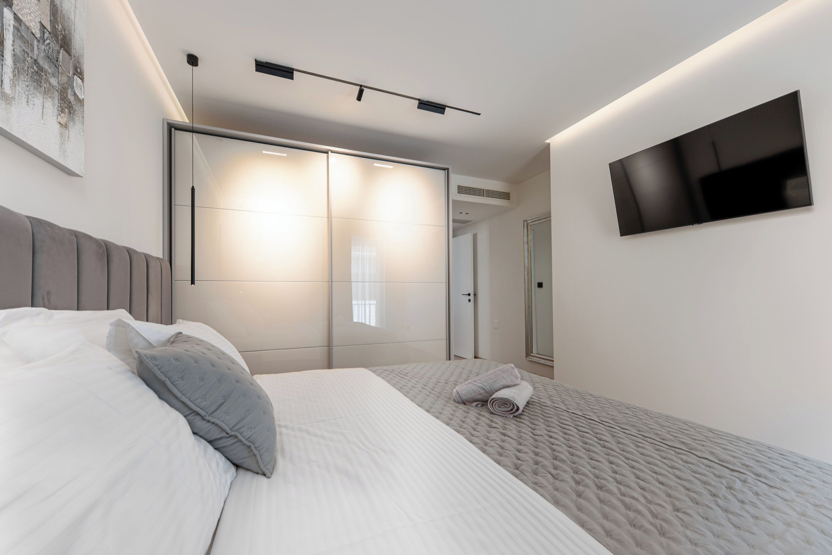 Une chambre à coucher moderne avec un grand lit, un téléviseur à écran plat et une porte de placard coulissante.