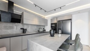 A modern kitchen with a marble countertop, stainless steel appliances, and a dining area with a bench. - Apartment Luka (Baska Voda)