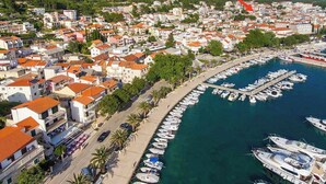 A coastal town with a marina, white buildings with red roofs, and a clear view of the sea. - Apartment Luka (Baska Voda)