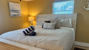 Ein Schlafzimmer mit einem Bett, Kissen, einer Nachttischlampe und einem Fenster mit Jalousien.