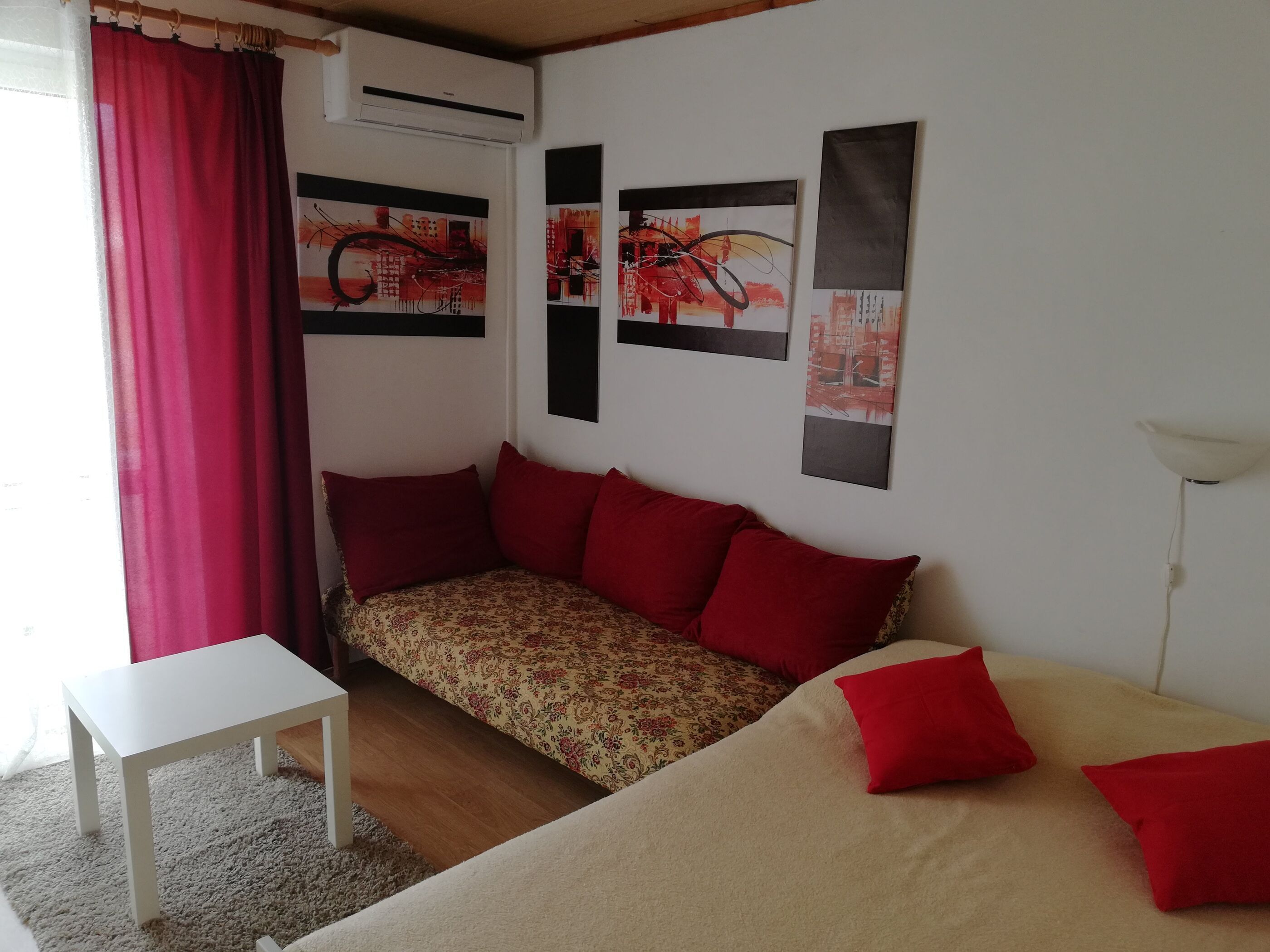 A living room with a sofa, a small table, and a red curtain.