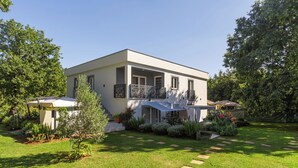 A modern two-story house with a balcony, surrounded by a well-maintained garden with stepping stones and various plants. - Apartments Cetri Hrasta (Pican)