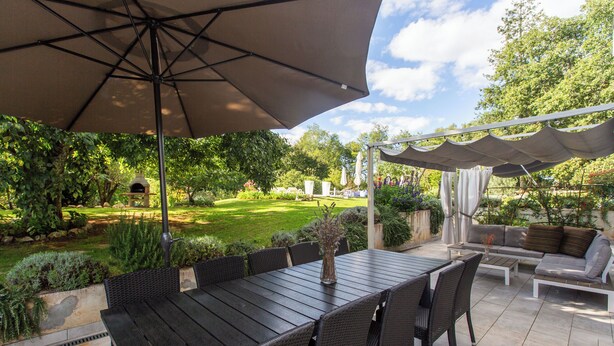 An outdoor patio with a dining table, chairs, and a large umbrella. - Apartments Cetri Hrasta (Pican)