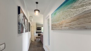 A hallway with a kitchen area visible in the background, featuring a modern design with a pendant light and artwork on the walls. - Apartments Cetri Hrasta (Pican)