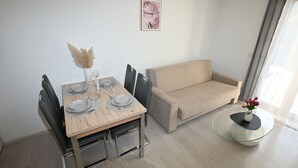 A dining area with a wooden table set for four, a beige sofa, and a glass coffee table with a vase of flowers. - Apartment Milankovic (Vrsar)