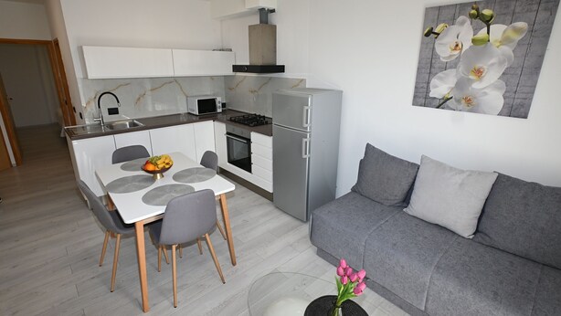 A modern kitchen with white cabinets, a built-in microwave, and a gas stove. - Apartment Milankovic (Vrsar)