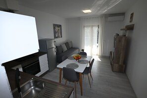 A compact kitchen with a dining table, chairs, and a refrigerator. - Apartment Milankovic (Vrsar)