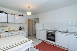 A compact kitchen with white cabinets, a microwave, a coffee maker, a refrigerator, and a dishwasher. - House Toni (Rab)