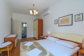 A hotel room with a bed, bedside table, desk, chair, and a ceiling light fixture. - House Toni (Rab)