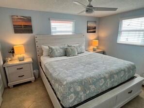 A bedroom with a bed, nightstands, a ceiling fan, and artwork on the walls. - Casa Blanca - Villa C12 (Sarasota)