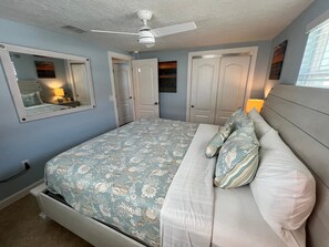 Ein Schlafzimmer mit einem Bett, einem Deckenventilator und zwei Türen.